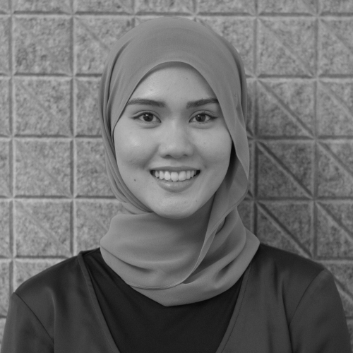 Close up portrait of a smiling woman wearing a hijab against a brick wall background